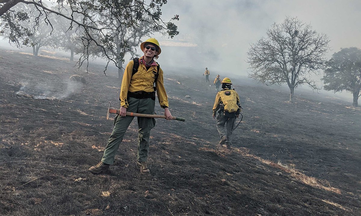 Fire ecology graduate student and research technician with the U.S. Forest Service Ashley Grupenhoff standing in a smoky wooded area.